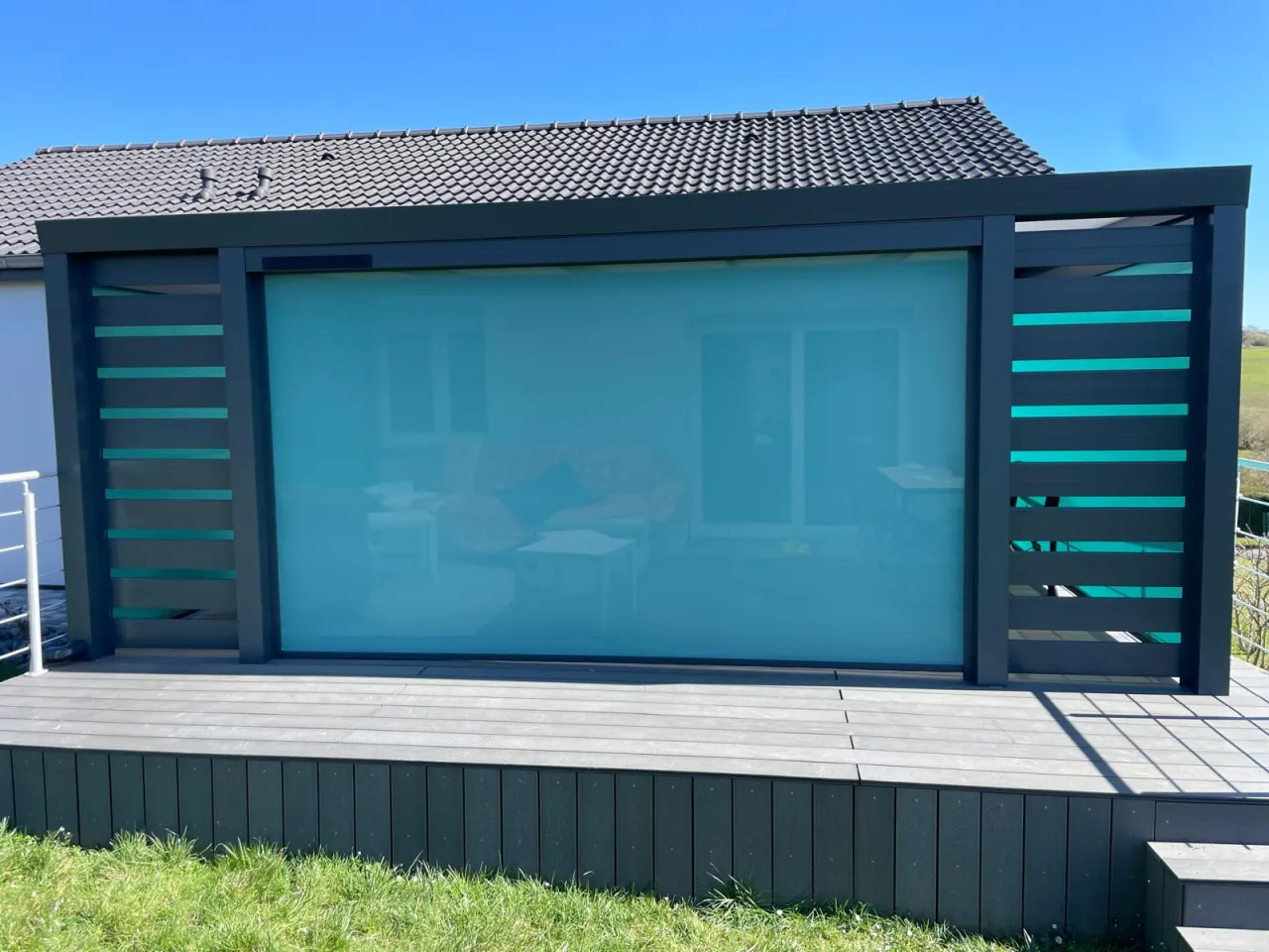 Store screen zip solaire coffre Gris anthracite et Toile Bleu turquoise pose sur pergola entre poteaux.