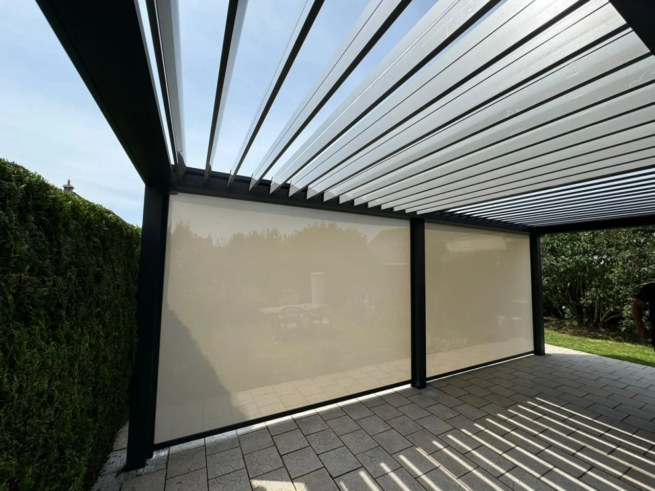 Store screen zip solaire coffre Gris anthracite et Toile ivoire clair pose sur pergola entre poteaux.