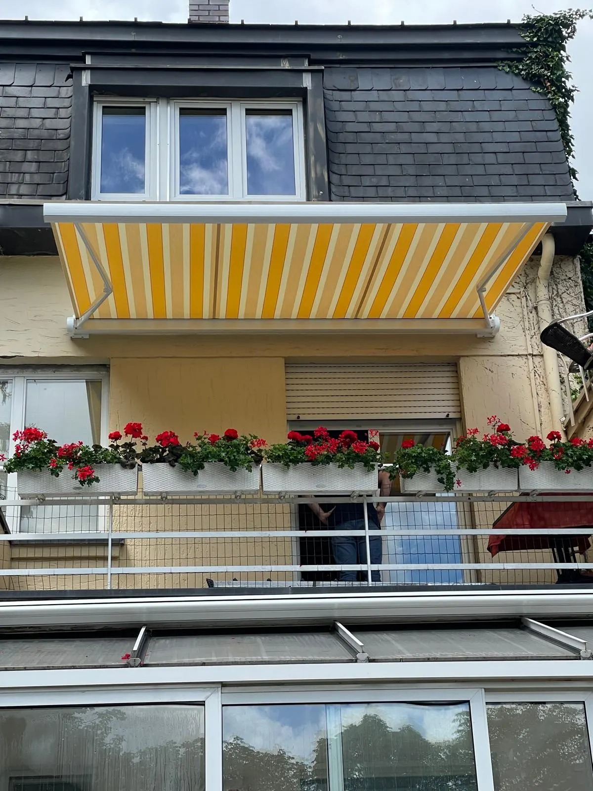 Store banne motorisé commande radio avec Toile décorative jaune et Ossature blanche avec Bras avec Leds intégrées.
