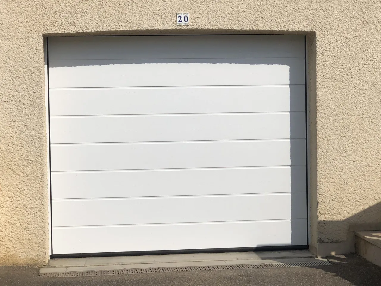 Porte de garage sectionnelle en aluminium laqué blanc avec épaisseur de 42 mm isolante avec manoeuvre motorisée et design lisse