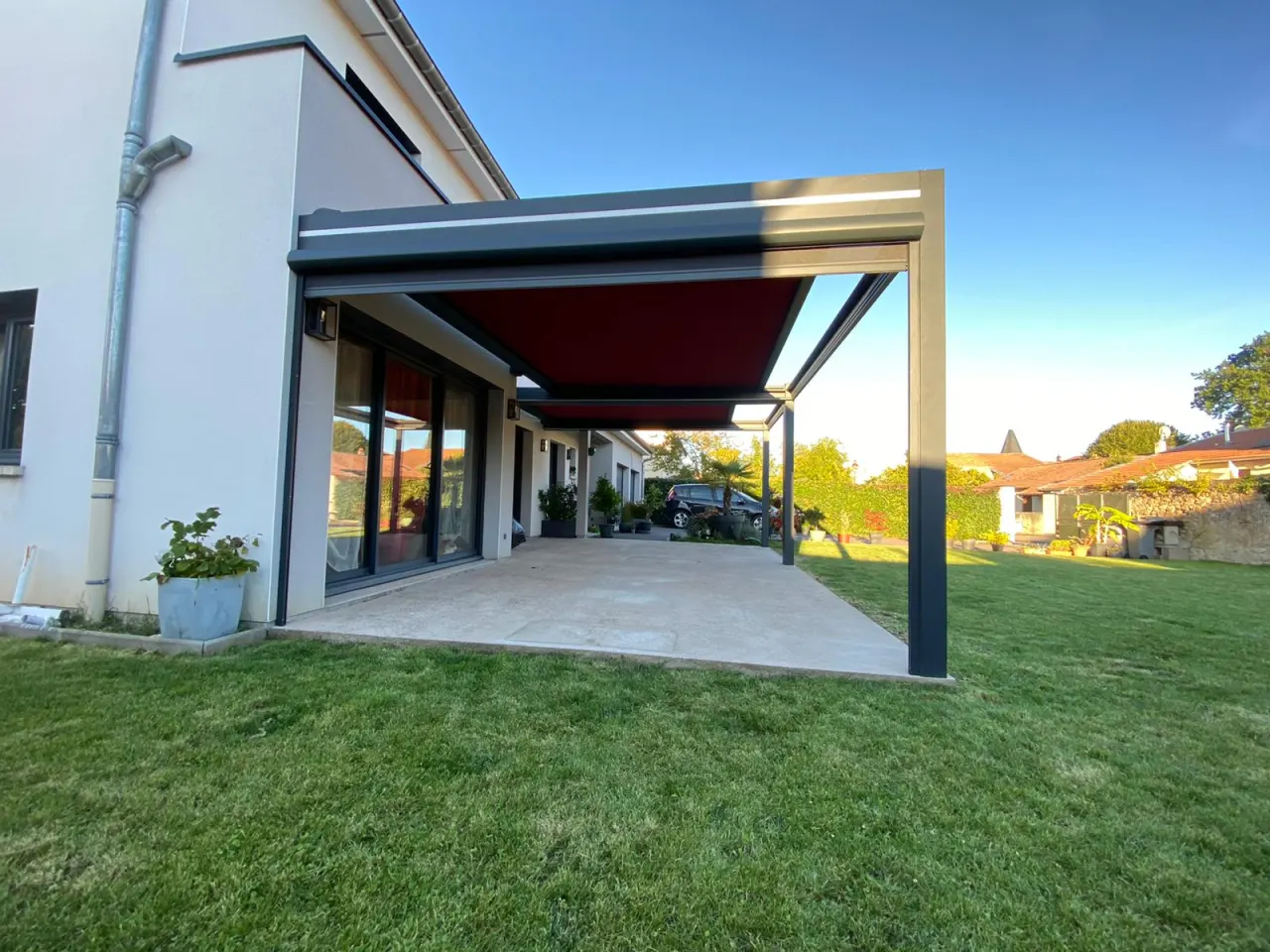 Pergola store avec ossature en aluminium laquée gris anthracite avec toile rouge pourpre
