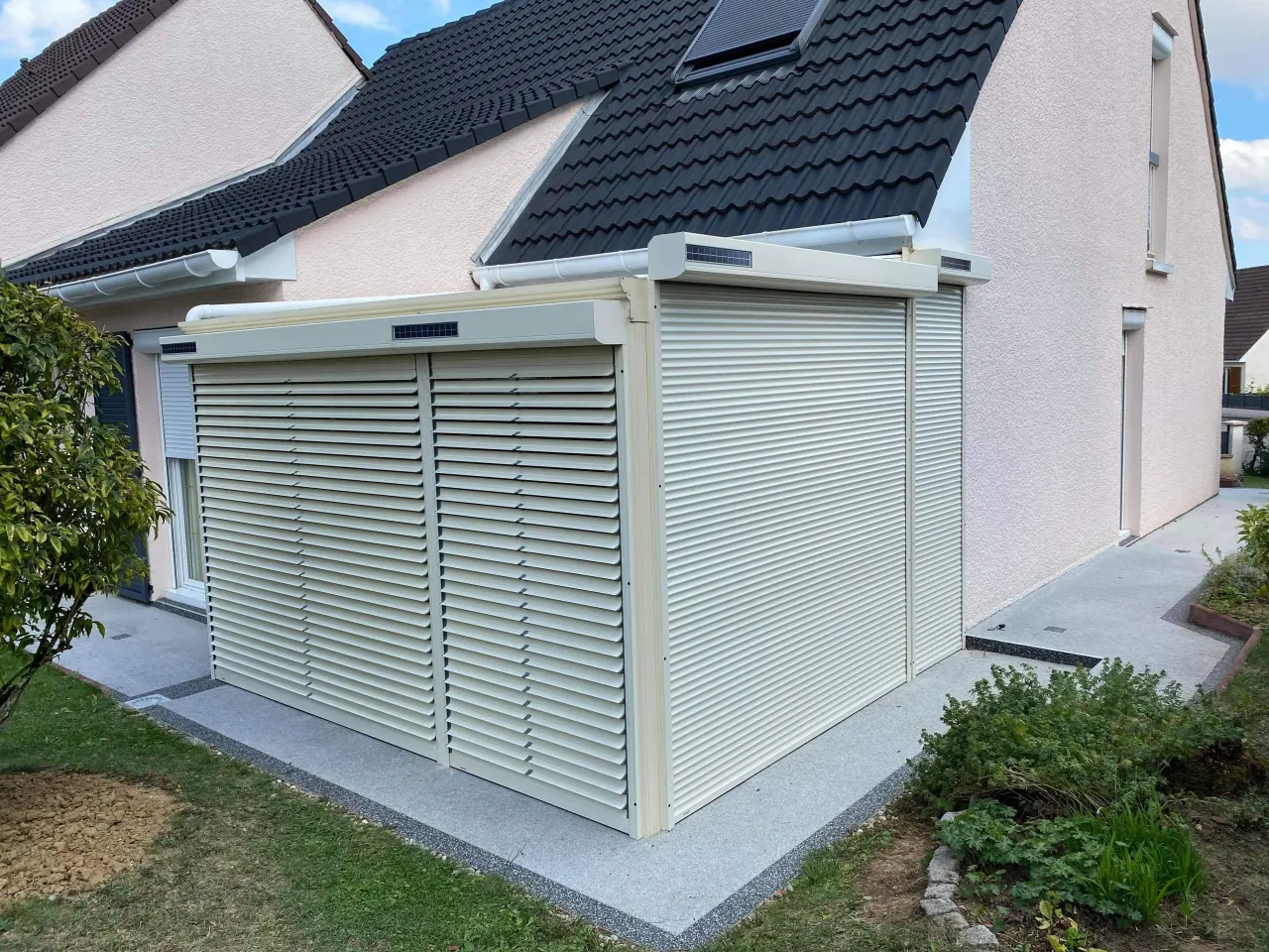 Volets roulants solaires motorisés en aluminium avec une pose sur véranda existante laqué ivoire clair avec capteurs solaires