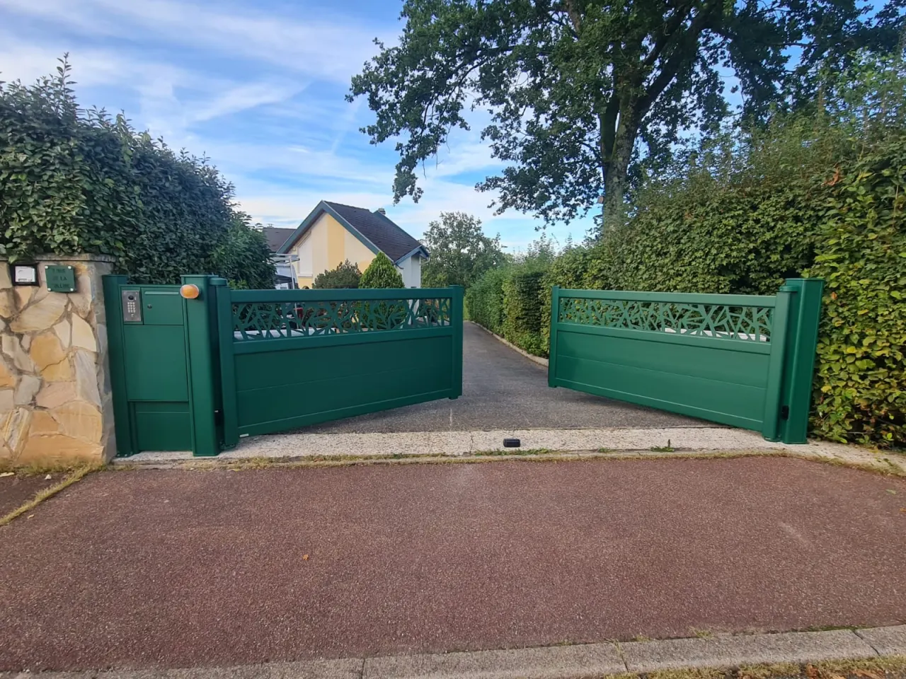 Portail battant 2 vantaux motorisés en aluminium laqué vert mousse avec motifs et soubassement plein