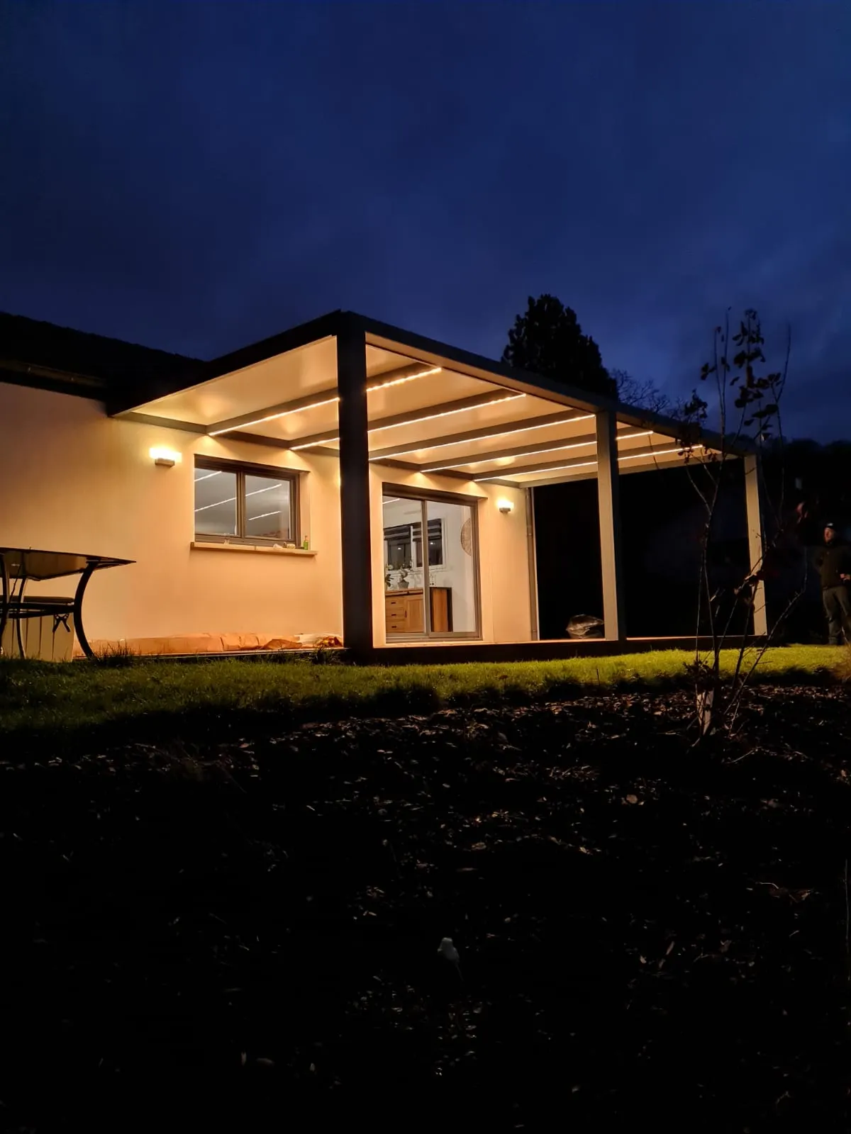Pergola fixe avec ossature en aluminium laquée gris anthracite avec toiture panneaux sandwich et éclairage leds intégrés dans les chevrons