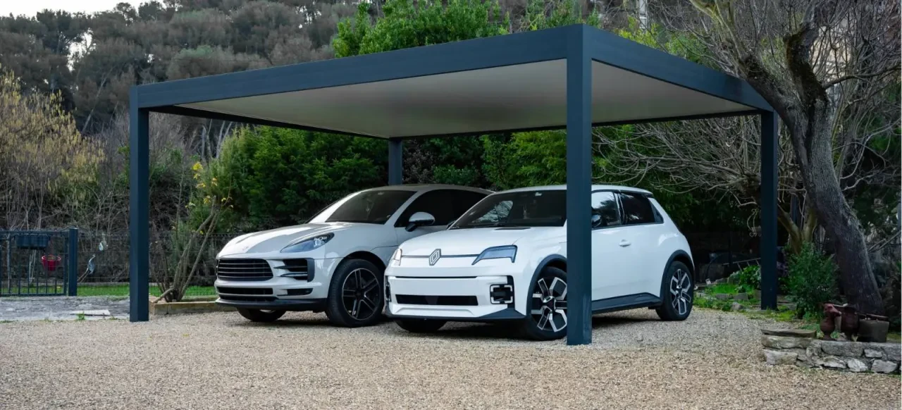 Carport à toit plat abritant deux véhicules devant un jardin