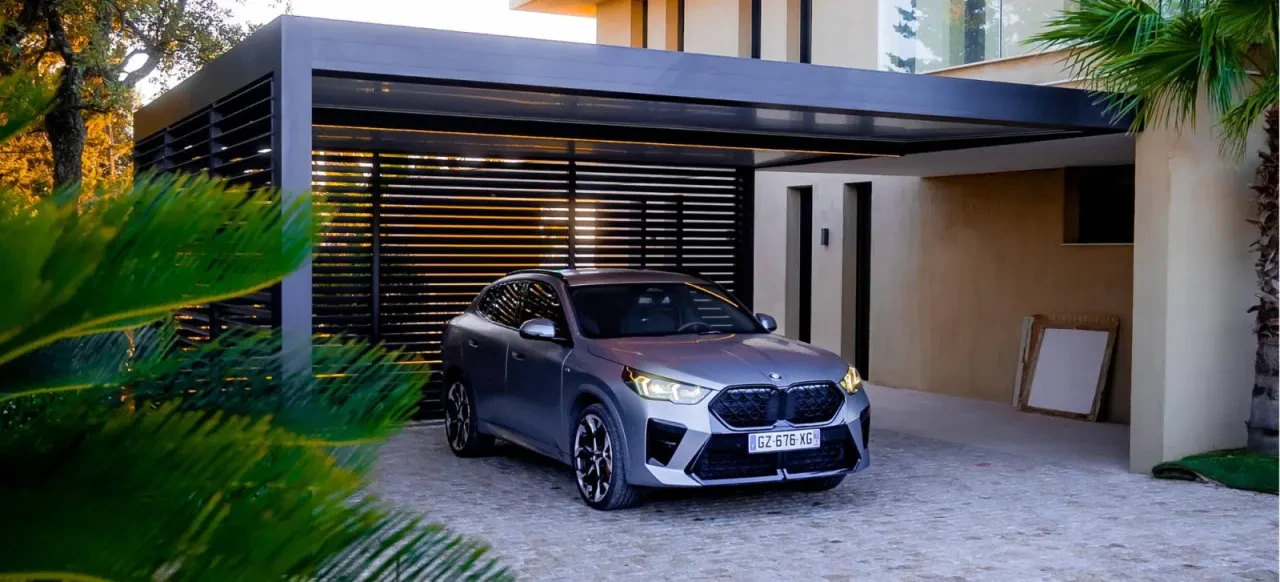 Carport contemporain accolé à une maison, avec un habillage à lames sur le côté