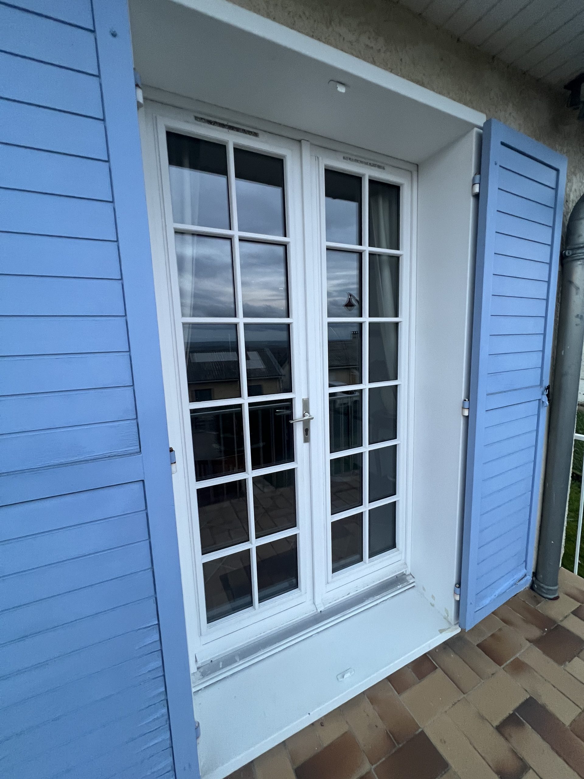 Porte fenêtres en PVC laqué blanc avec croisillons et ouvrant dormant renforcés et volets battants bleu ciel