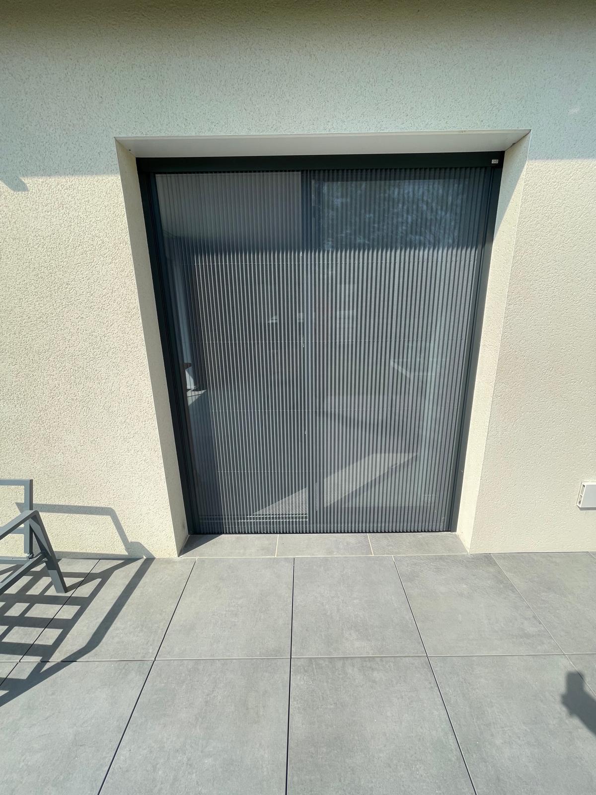 Moustiquaire plissée avec ossature en aluminium laquée gris anthracite avec toile fibre de verre grise