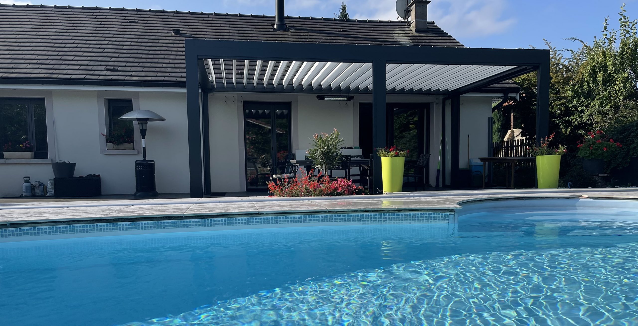 Pergola bioclimatique avec ossature en aluminium laquée gris anthracite avec lames orientables en aluminium laquées blanc