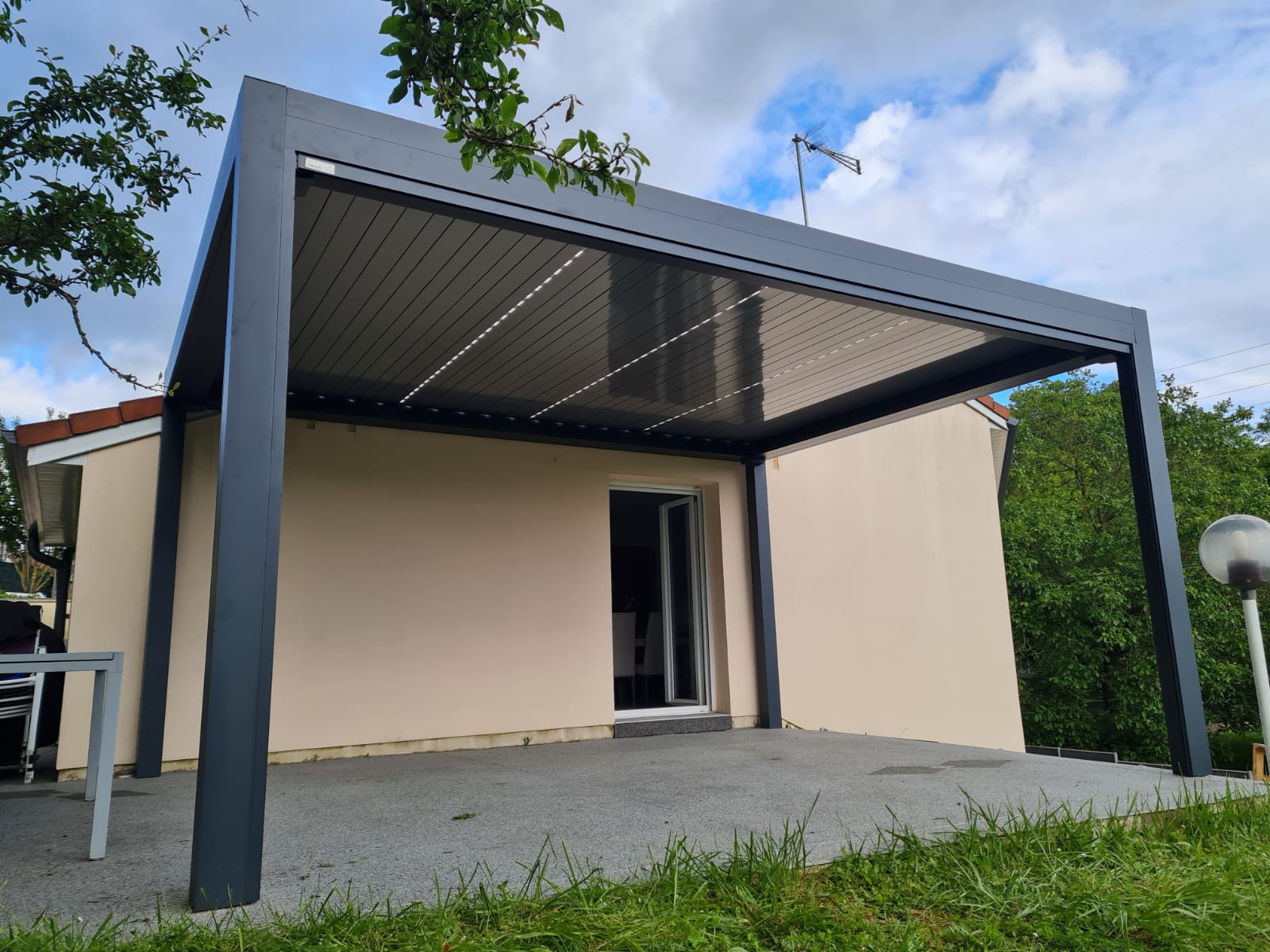 Pergola bioclimatique avec ossature en aluminium laqué gris anthracite avec lames orientables en aluminium laqué blanc avec éclairage leds intégré