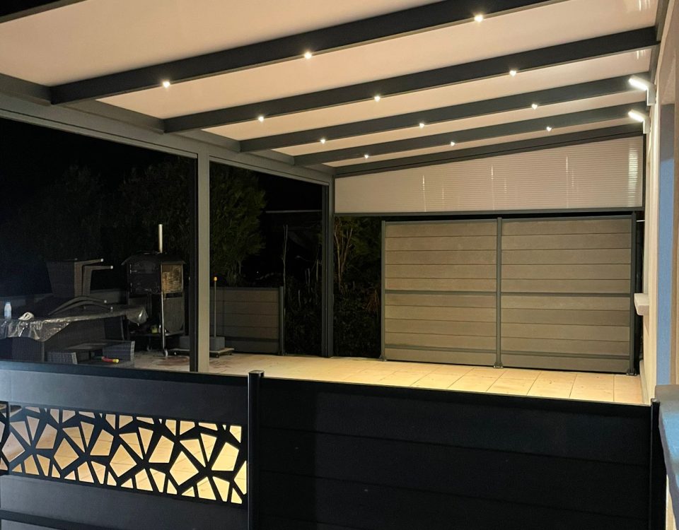 Pergola fixe avec ossature en aluminium laquée gris anthracite avec toiture panneaux sandwich et éclairage spots leds intégrées dans les chevrons