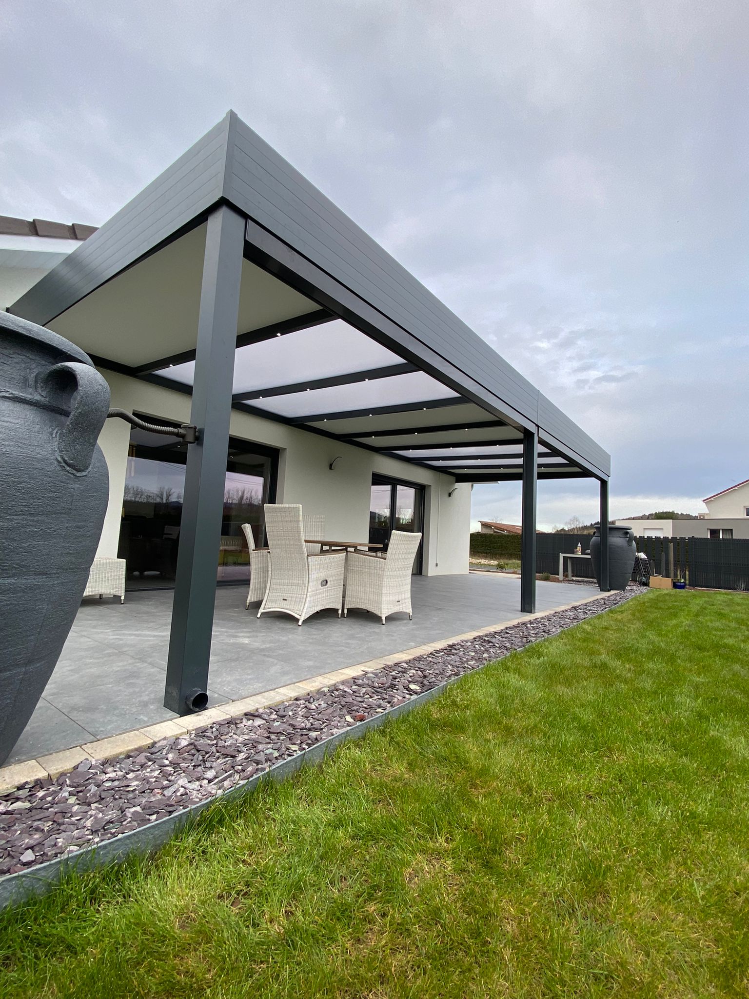 Pergola fixe avec ossature en aluminium laquée gris anthracite avec toiture panneaux sandwich et panneaux polycarbonates 32mm et éclairage spots leds intégrés dans les chevrons