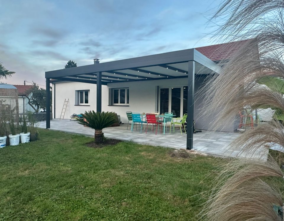 Pergola fixe avec ossature en aluminium laquée gris anthracite avec toiture panneaux sandwich et éclairage spots leds intégrés dans les chevrons