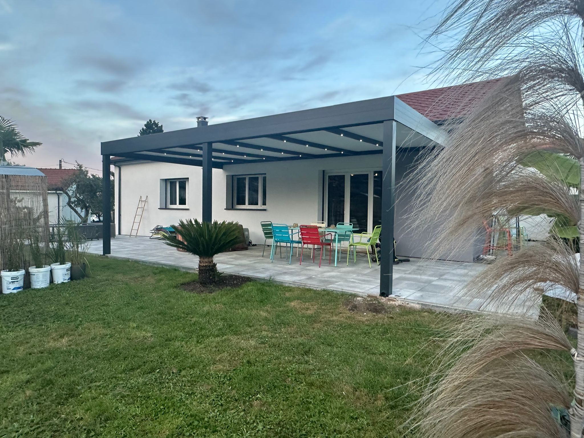 Pergola fixe avec ossature en aluminium laquée gris anthracite avec toiture panneaux sandwich et éclairage spots leds intégrés dans les chevrons