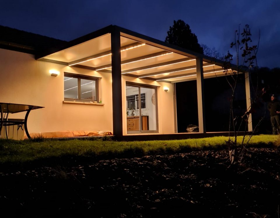 Pergola fixe avec ossature en aluminium laquée gris anthracite avec toiture panneaux sandwich et éclairage leds intégrés dans les chevrons