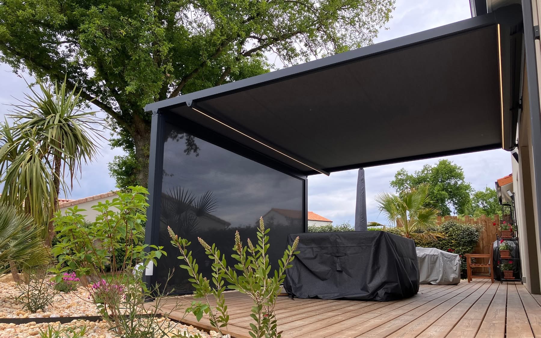 Pergola store avec ossature en aluminium laqué gris anthracite avec toile grise anthracite avec bandeau led avec store gris anthracite en façade