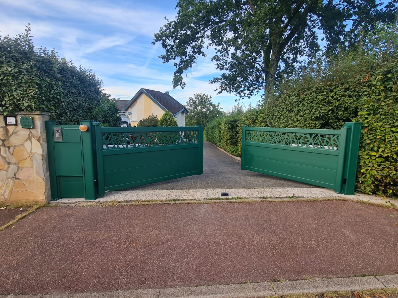 Portail battant 2 vantaux motorisés en aluminium laqué vert mousse avec motifs et soubassement plein