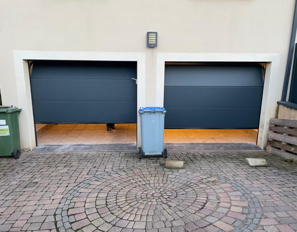 Portes de garages sectionnelles en aluminium laquées gris anthracite avec manoeuvre motorisée et design lisse