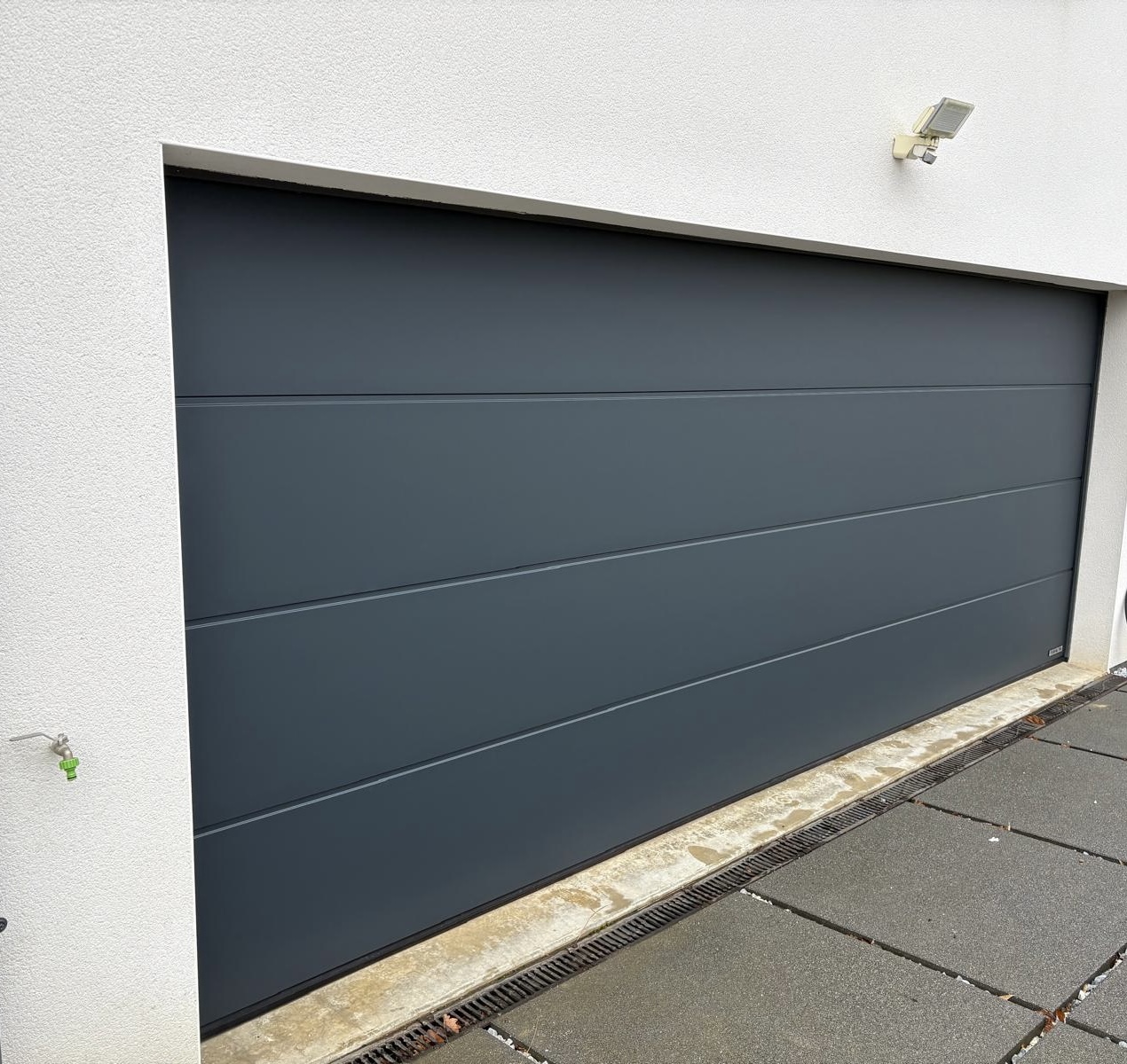 Porte de garage sectionnelle en aluminium laquée gris anthracite avec manoeuvre motorisée et design lisse