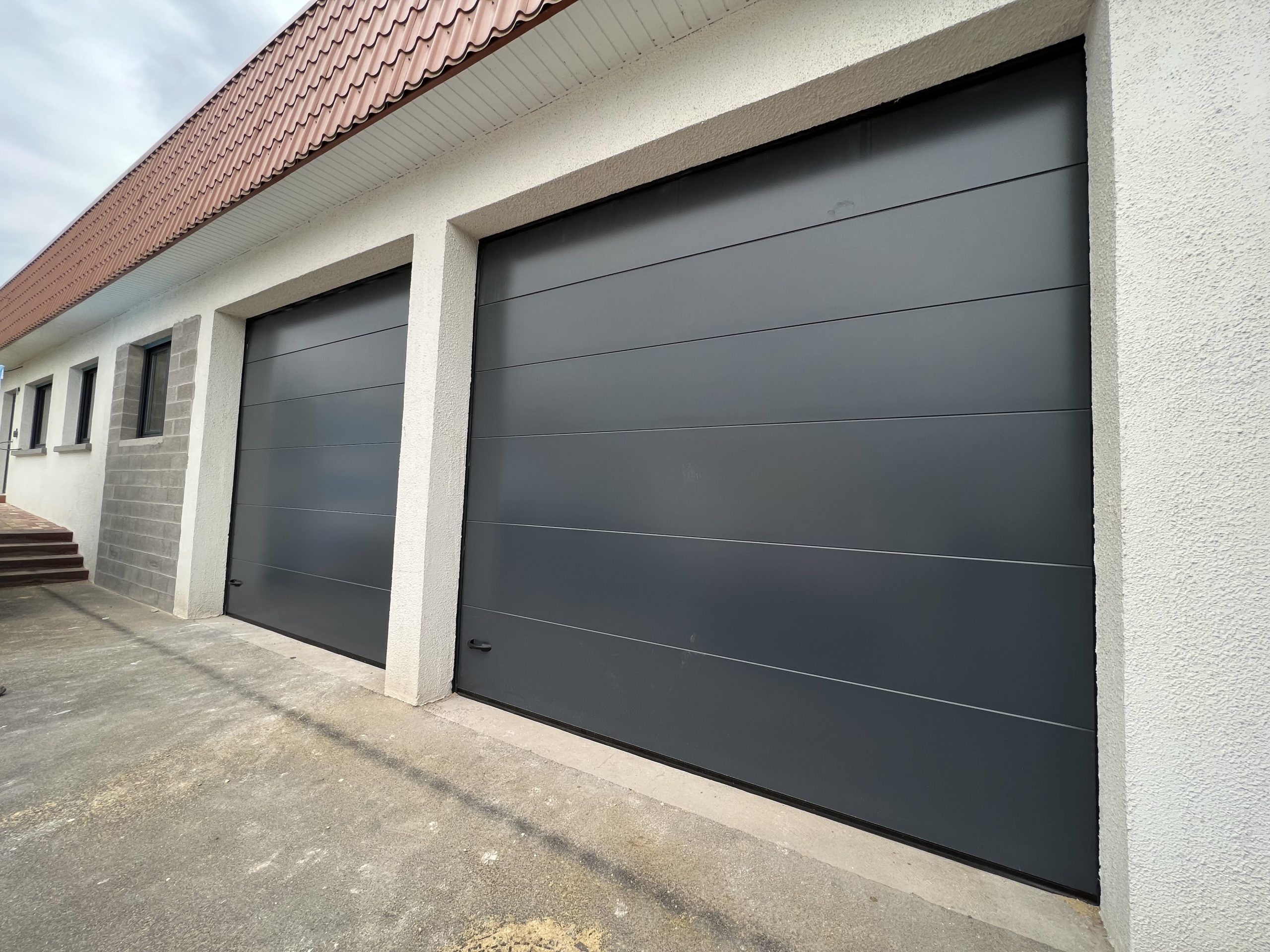 Portes de garages sectionnelles en aluminium laquées gris anthracite avec manoeuvre motorisée et design lisse