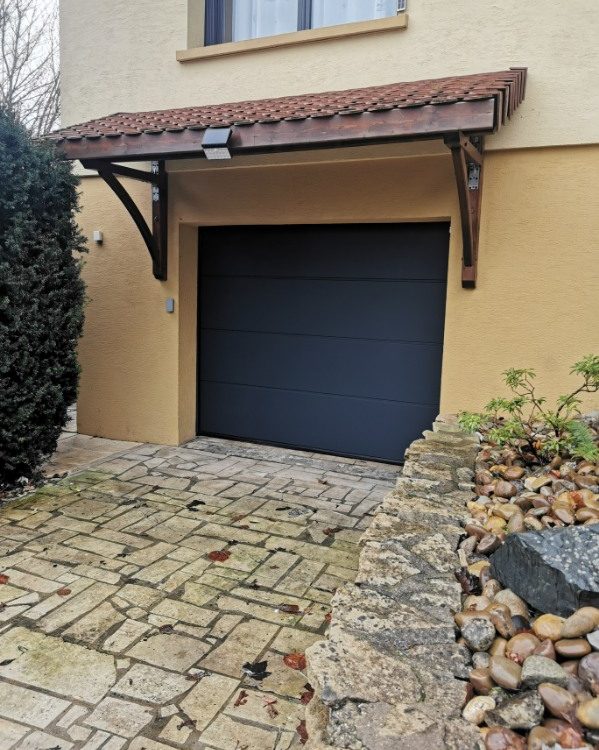 Porte de garage sectionnelle en aluminium laquée gris anthracite avec manoeuvre motorisée et design lisse