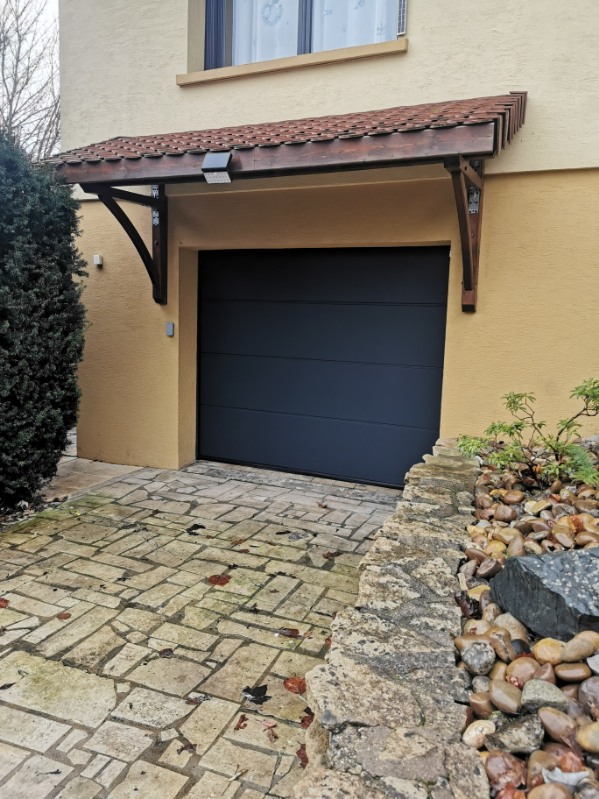 Porte de garage sectionnelle en aluminium laquée gris anthracite avec manoeuvre motorisée et design lisse