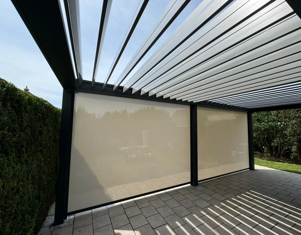 Store screen zip solaire coffre Gris anthracite et Toile ivoire clair pose sur pergola entre poteaux.