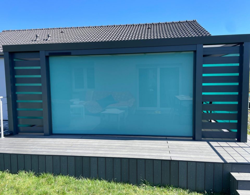 Store screen zip solaire coffre Gris anthracite et Toile Bleu turquoise pose sur pergola entre poteaux.