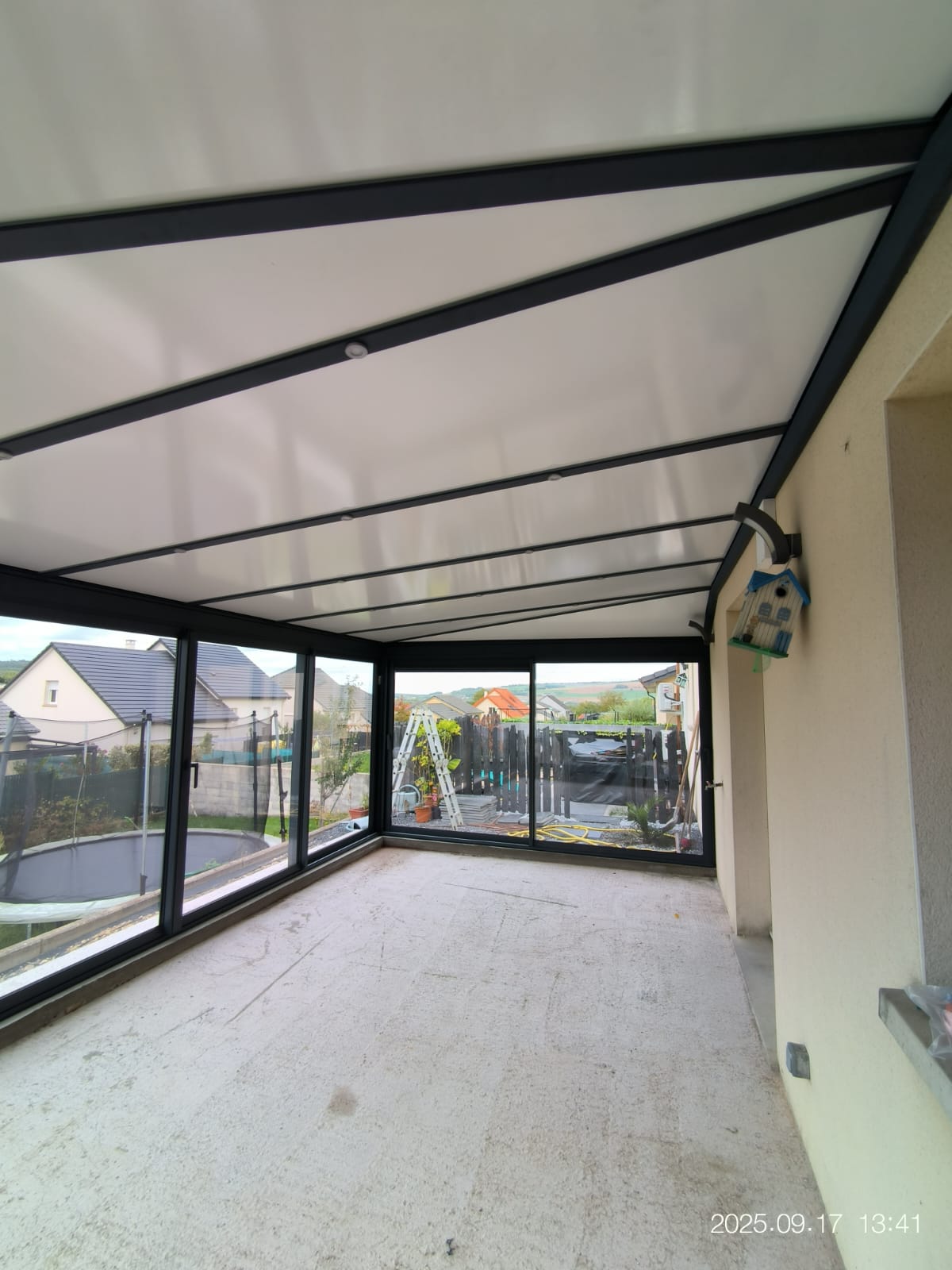 Véranda en aluminium laqué gris anthracite Vue intérieur avec toiture en aluminium isolé 85mm blanc intérieur/ardoise extérieur avec spots Leds intégrés dans les chevrons