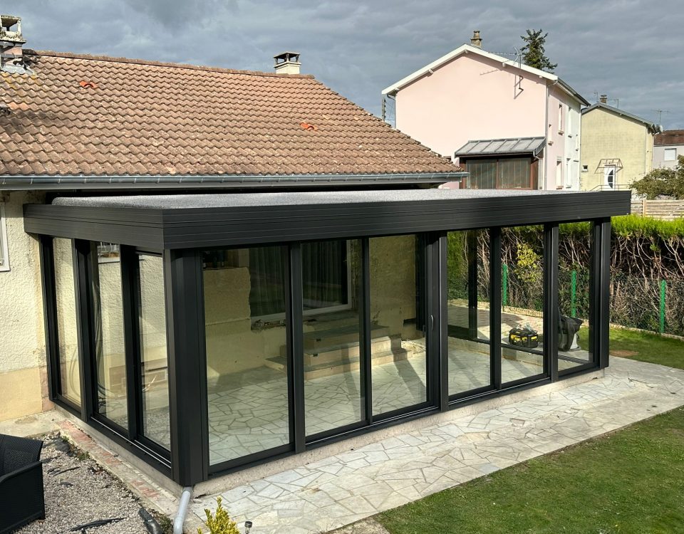 Véranda en aluminium laqué gris anthracite avec toiture en aluminium isolé 85mm blanc intérieur/gazon synthétique isophonique extérieur