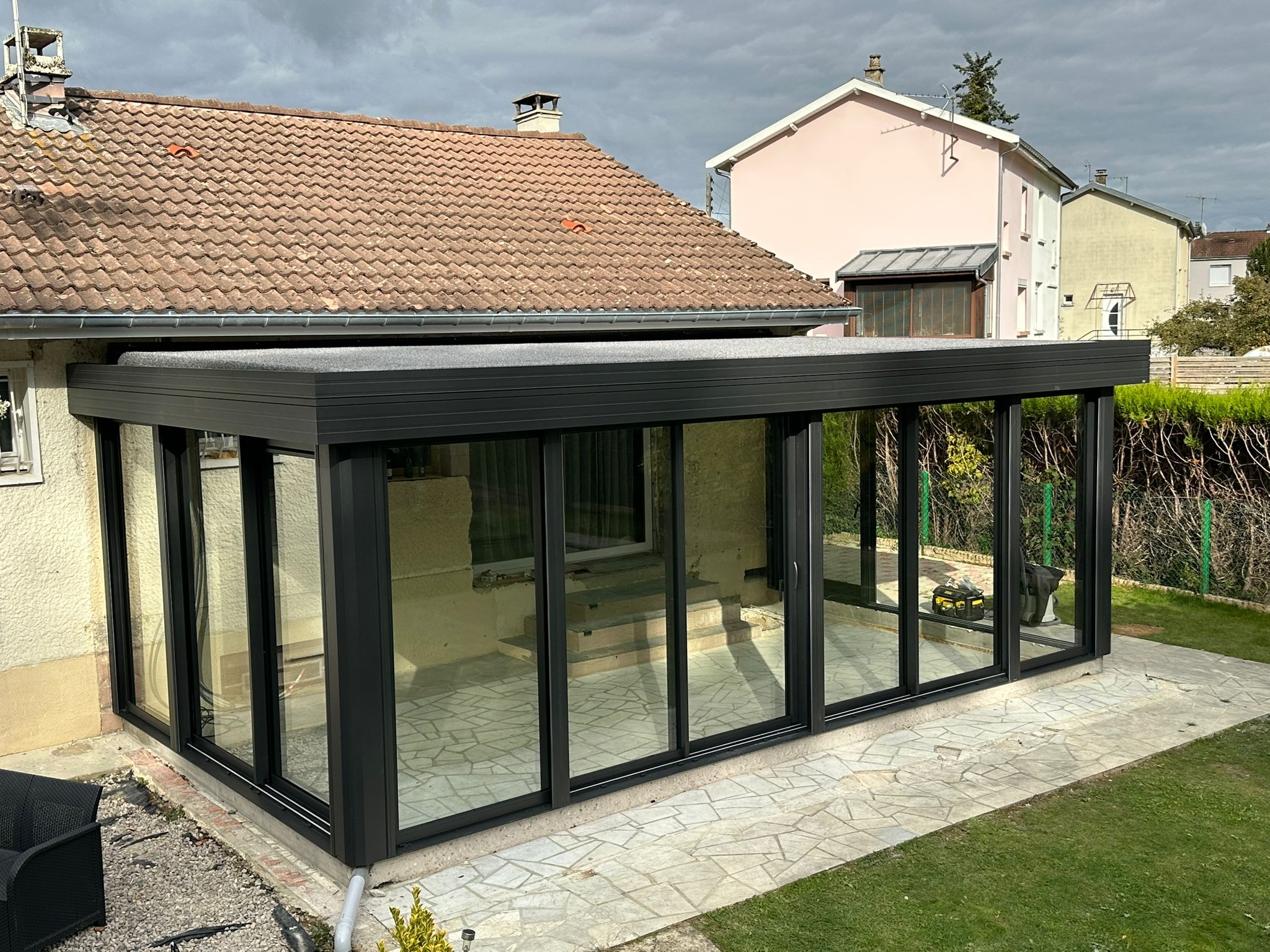 Véranda en aluminium laqué gris anthracite avec toiture en aluminium isolé 85mm blanc intérieur/gazon synthétique isophonique extérieur