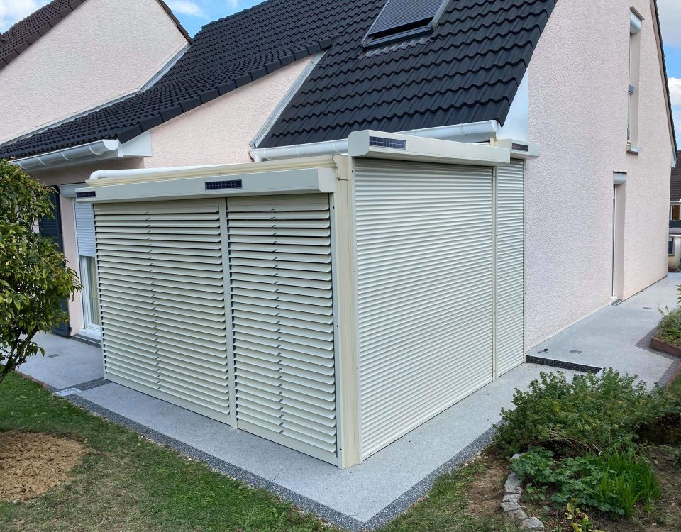 Volets roulants solaires motorisés en aluminium avec une pose sur véranda existante laqué ivoire clair avec capteurs solaires