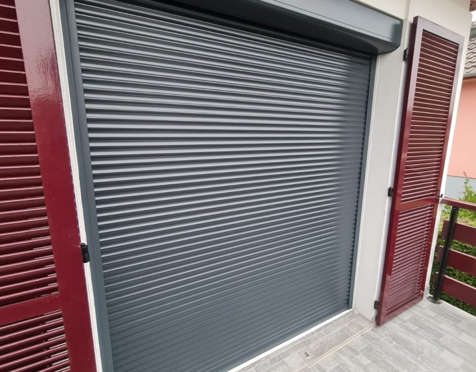 Volets roulant motorisés solaires en aluminium laqué gris anthracite avec capteurs solaire avec une pose sous linteau avec volets battants laqués rouges bordeaux