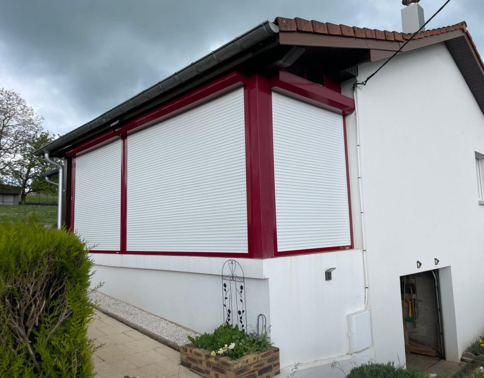 Volets roulants motorisés laqués blanc avec une pose sur véranda existante avec véranda laqué rouge pourpre