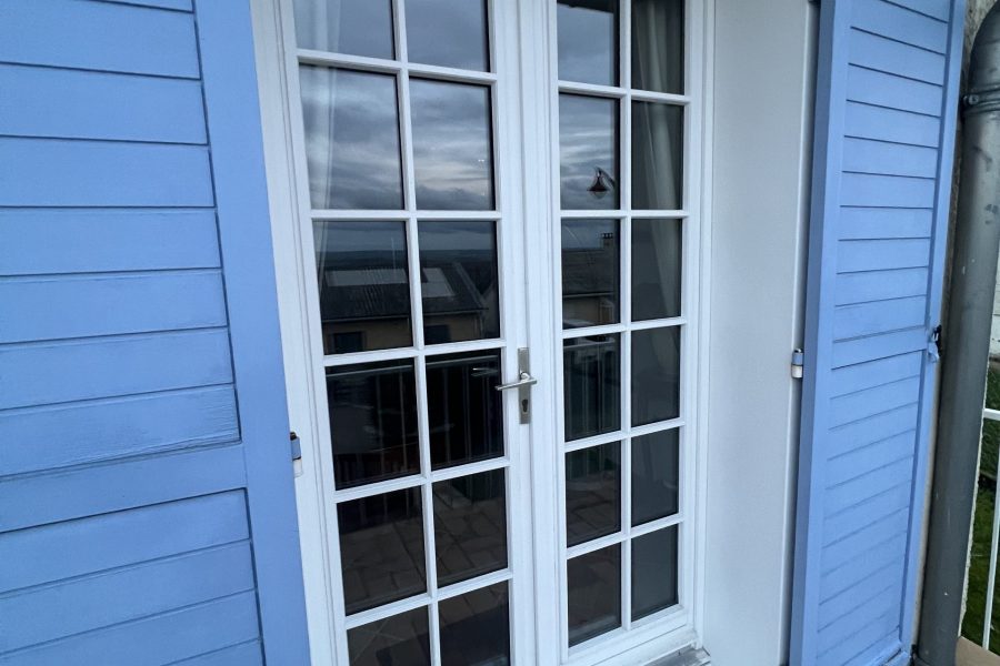 Porte fenêtres en PVC laqué blanc avec croisillons et ouvrant dormant renforcés et volets battants bleu ciel