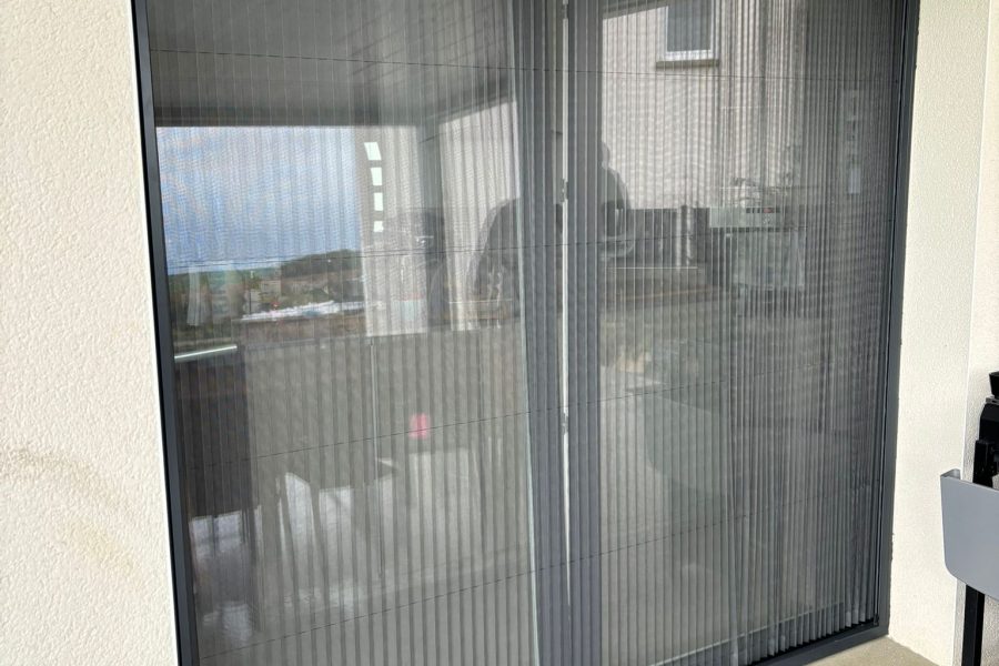 Moustiquaire plissée avec ossature en aluminium laquée gris anthracite toile fibre de verre grise