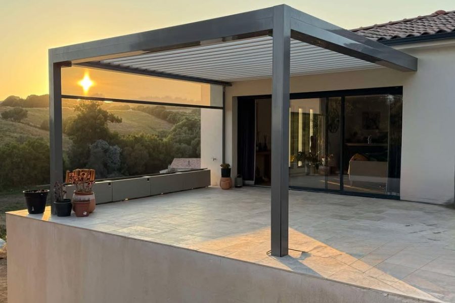 Pergola bioclimatique avec ossature en aluminium laquée gris anthracite avec lames orientables en aluminium laquées blanc et store zip latéral gris anthracite intégré