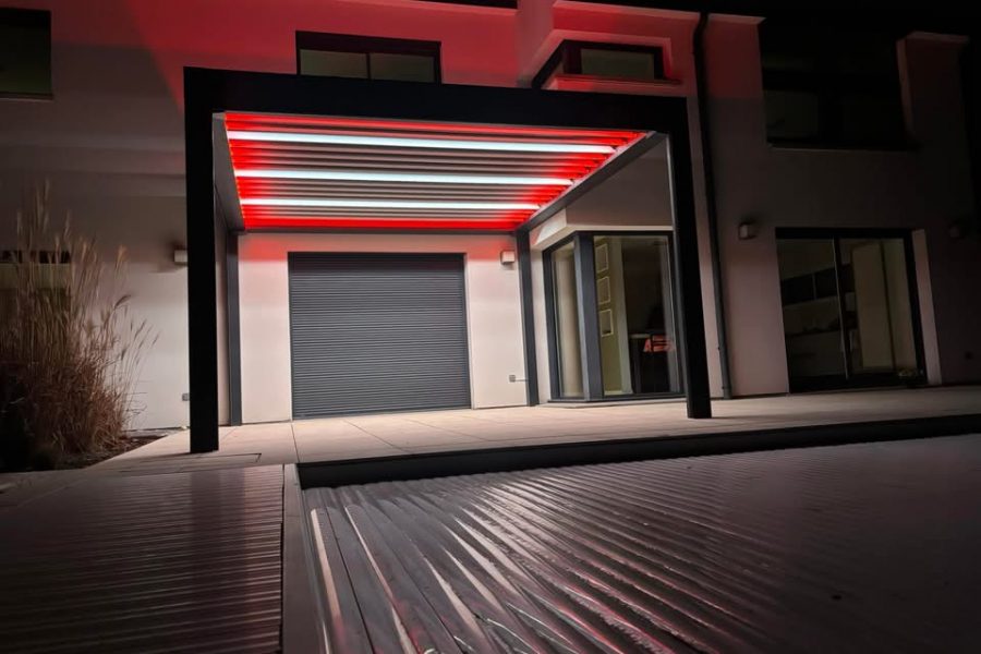 Pergola bioclimatique avec ossature en aluminium laquée gris anthracite avec lames orientables en aluminium laquées blanc avec éclairage leds intégré dans les lames et éclairage leds RGB intégré en périphérie