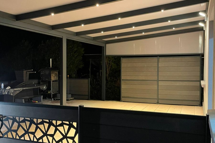 Pergola fixe avec ossature en aluminium laquée gris anthracite avec toiture panneaux sandwich et éclairage spots leds intégrées dans les chevrons