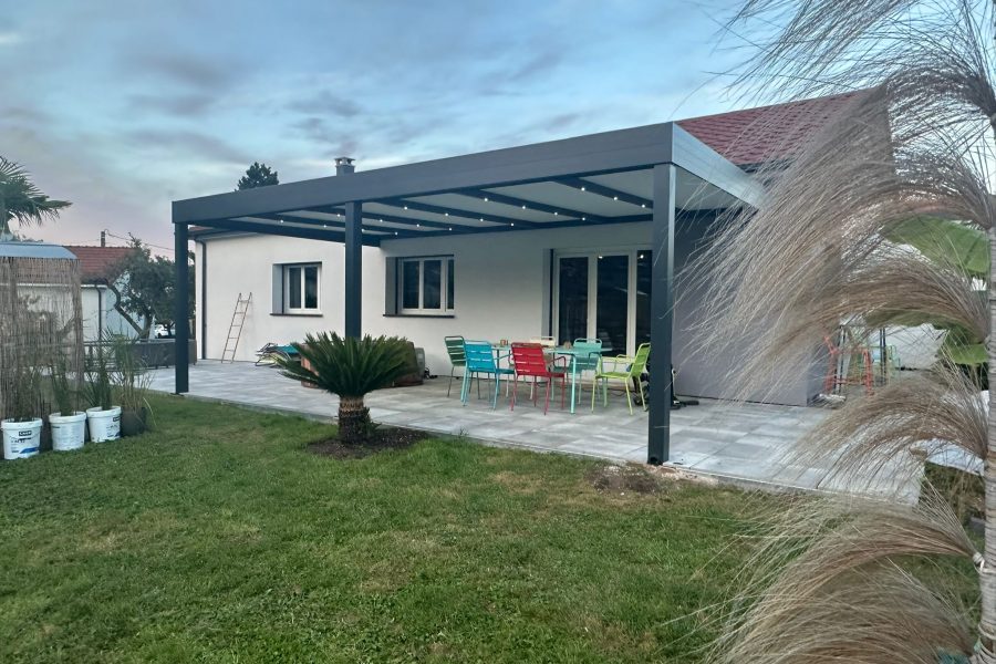 Pergola fixe avec ossature en aluminium laquée gris anthracite avec toiture panneaux sandwich et éclairage spots leds intégrés dans les chevrons