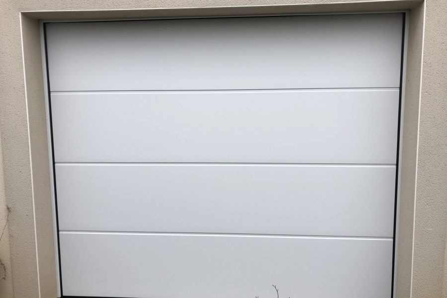 Porte de garage sectionnelle en aluminium laquée blanc avec manoeuvre motorisée et design lisse