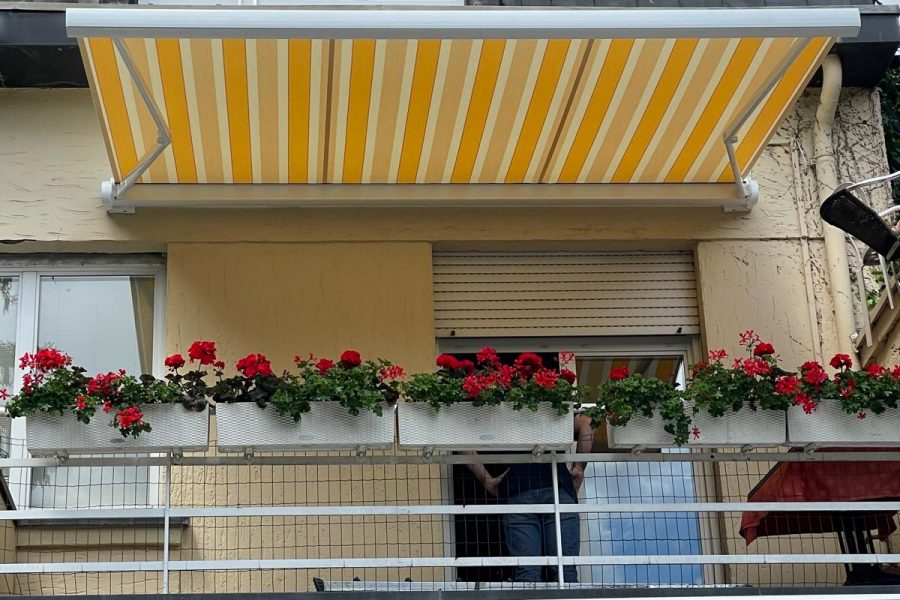 Store banne motorisé commande radio avec Toile décorative jaune et Ossature blanche avec Bras avec Leds intégrées.