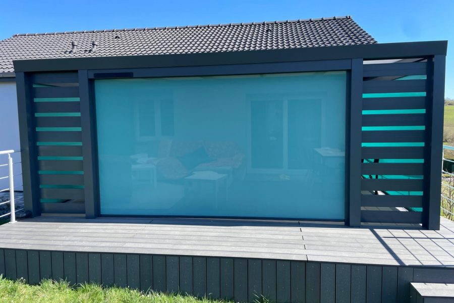 Store screen zip solaire coffre Gris anthracite et Toile Bleu turquoise pose sur pergola entre poteaux.