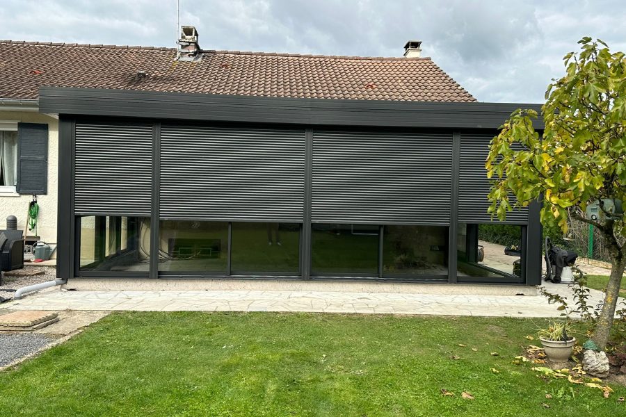 Véranda en aluminium laquée gris anthracite avec toiture en aluminium isolé 85mm blanc intérieur/ardoise extérieur avec volets roulant motorisés intégrés laqué gris anthracite .