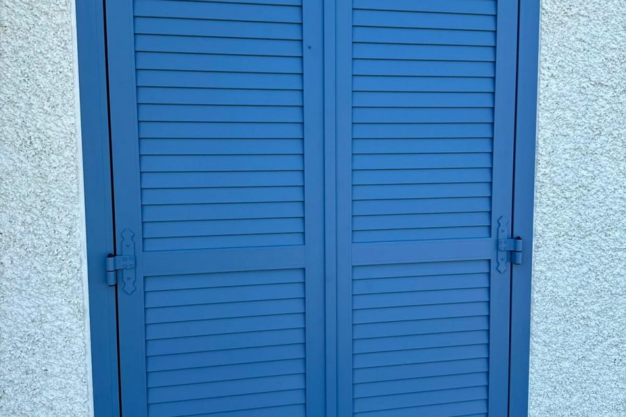 Volets battants en aluminium laqué bleu ciel avec persienne non ajourée avec pré-cadre pour plus d’obscurité et une meilleure finition avec crémone