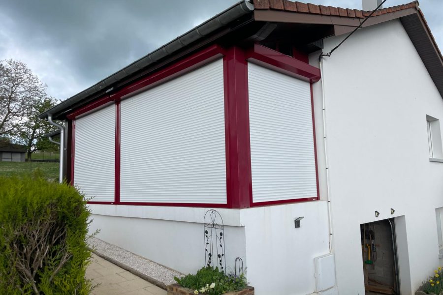 Volets roulants motorisés laqués blanc avec une pose sur véranda existante avec véranda laqué rouge pourpre